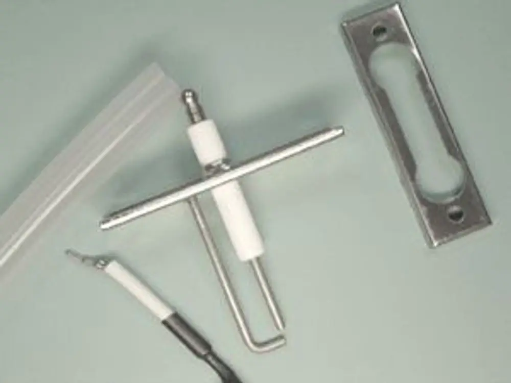 Zündelektrode von Remeha, bestehend aus einem metallischen Stift, einer Halterung und Draht. Teile liegen auf einer grauen Oberfläche.